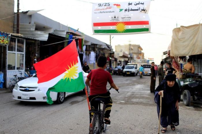 A boy rides a bicycle with the flag of Kurdistan in Tuz Khurmato, Iraq September 24, 2017.