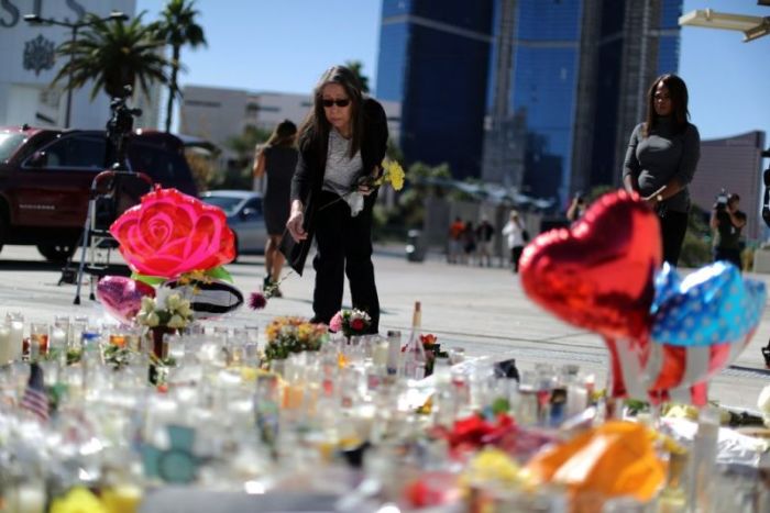 A woman leaves flowers at a makeshift memorial on the Las Vegas Strip for victims of the Route 91 music festival mass shooting next to the Mandalay Bay Resort and Casino in Las Vegas, Nevada.