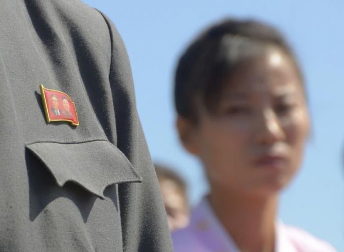 A participant wears a badge with portraits of North Korean former leaders Kim Il-sung (L) and Kim Jong-il during a ceremony to mark the re-opening of a railway link between North Korea and Russia at the port of Rajin, North Korea September 22, 2013.