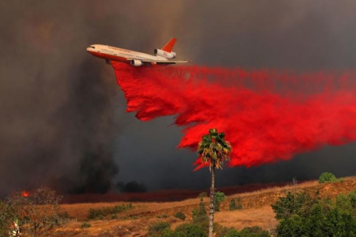 A DC-10 aircraft drops fire retardant on a wind driven wildfire in Orange, California, U.S., October 9, 2017.