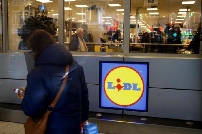 A woman walks past a logo inside a store of discount supermarket chain Lidl in Paris, France, March 1, 2016.