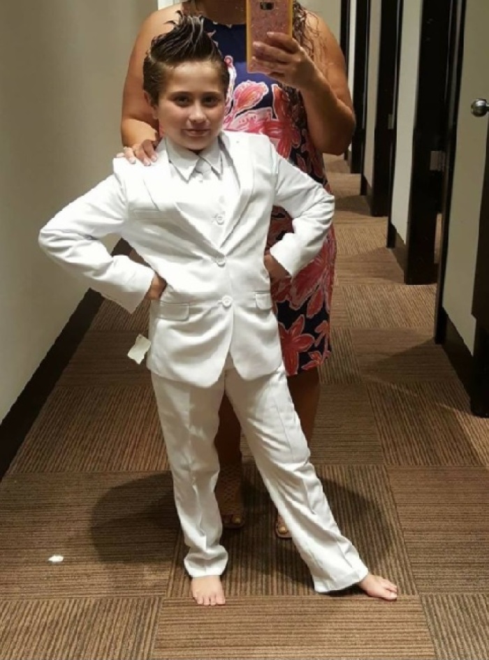 9-year-old Cady Mansell trying on a suit. Cady's mother Chris garnered headlines when she posted to social media claiming that her daughter was denied First Communion over the church mandating that Cady wear a dress for the ceremony.