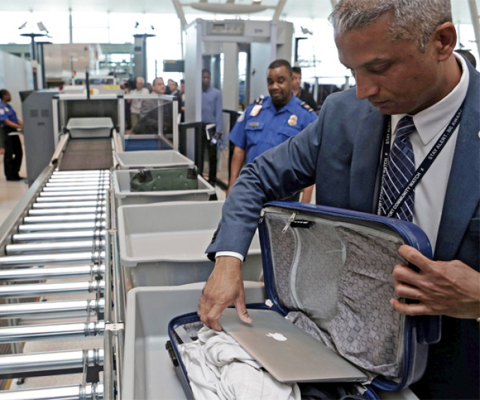 A TSA official removes a laptop from a bag for scanning using the Transport Security Administration's new Automated Screening System.