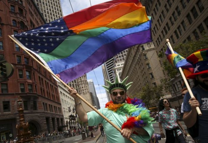 A man dressed as the Statue of Liberty carries a rainbow American flag while marching in a gay pride parade in San Francisco in this undated photo.