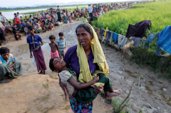 A Rohingya refugee woman who crossed the border from Myanmar a day before, carries her daughter and searches for help as they wait to receive permission from the Bangladeshi army to continue their way to the refugee camps, in Palang Khali, Bangladesh October 17, 2017.