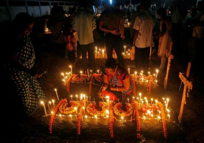 People light candles on the grave of their relatives before praying at a cemetery during the observance of All Souls Day in Agartala, India November 2, 2016.
