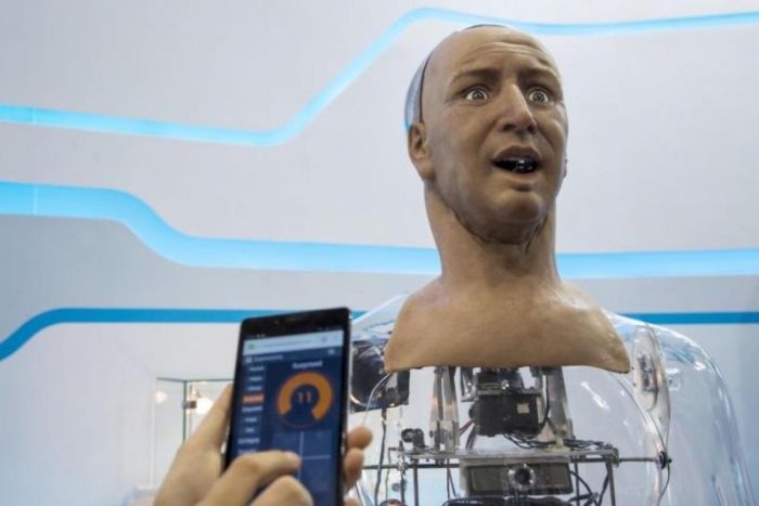 A staff controls the expressions of a humanoid robot named Han developed by Hanson Robotics via a mobile phone during the Global Sources spring electronics show in Hong Kong April 18, 2015.