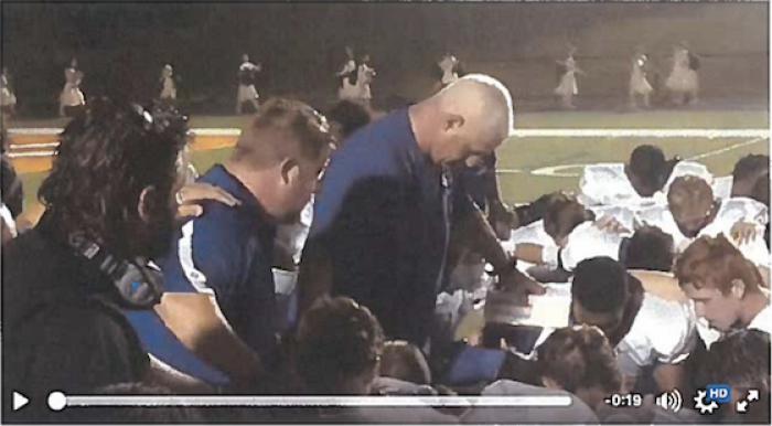 Coach John Small leads the East Coweta High School football team in prayer.