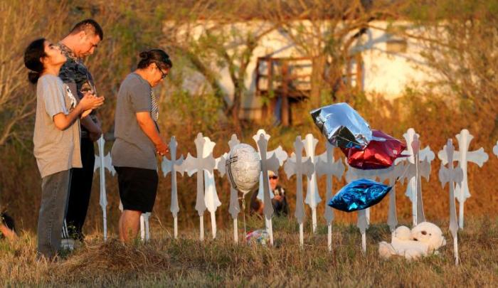 Miranda Hernandez (L) prays at sunset with father Kenneth and mother Irene at a row of crosses near the site of the shooting at the First Baptist Church of Sutherland, Texas, November 6, 2017.