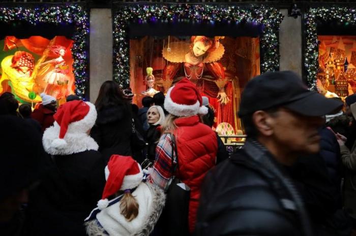 People wearing Christmas hats look in a shop window on Fifth Avenue during a busy shopping day in Manhattan, New York City, U.S. December 17, 2016.
