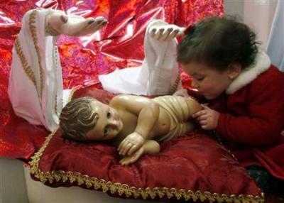 Credit : A child touches a statue of Baby Jesus in the Church of the Nativity in the West Bank town of Bethlehem December 25, 2006.