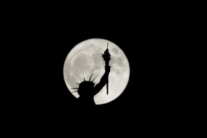 The rising supermoon is seen behind a statue on top of the Natural History Museum in Vienna, Austria November 14, 2016.