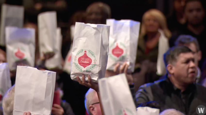 Willow Creek Church attendees hold up Christmas bags after filling them up with gifts to deliver to inmates in Illinois, Dec. 3, 2017.