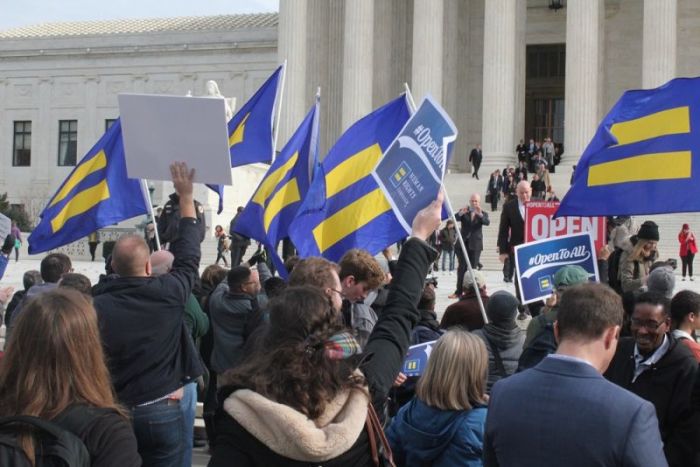 Supporters of same-sex couple David Mullins and Charlie Craig waving flags and holding from The Human Rights Campaign as attorneys exit the Supreme Court from the case Masterpiece Cakeshop v. Colorado Civil Rights Commission on December 5, 2017.