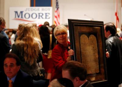 A framed Ten Commandments is being carried by a supporter at Republican Roy Moore's election party in Montgomery, Alabama, U.S., December 12, 2017.