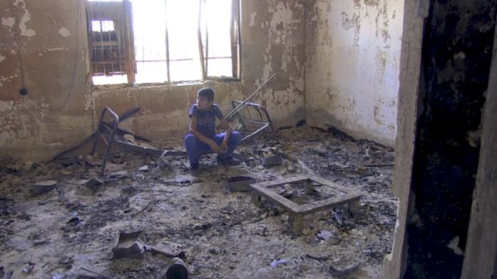 Noeh, a 12-year-old Iraqi Christian boy, squats down in what used to be his bedroom before it was burned down after the Islamic State took over large swaths of Iraq in 2014.