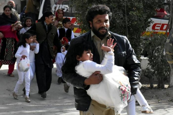 A man carries a girl as he runs out with others after gunmen attacked the Bethel Memorial Methodist Church in Quetta, Pakistan on Dec. 17, 2017.