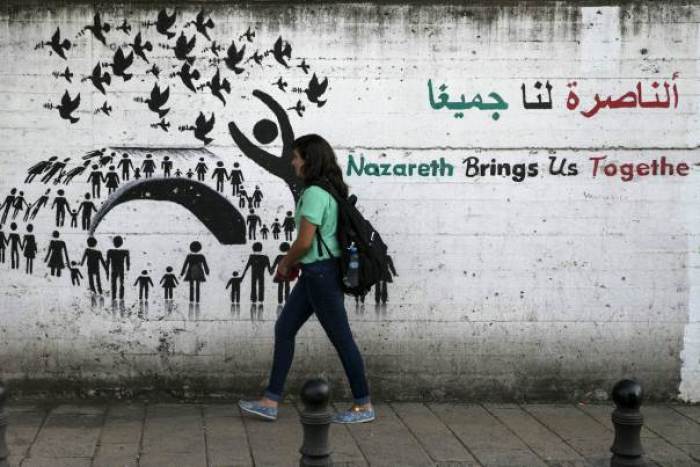 A youth walks past graffiti on a street in Nazareth, northern Israel October 12, 2015.