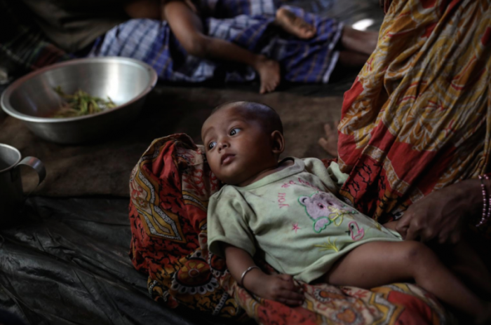 A Rohingya Hindu refugee woman holds her child inside their temporary shelter at the Kutupalong Hindu refugee camp near Cox's Bazar, Bangladesh December 17, 2017.