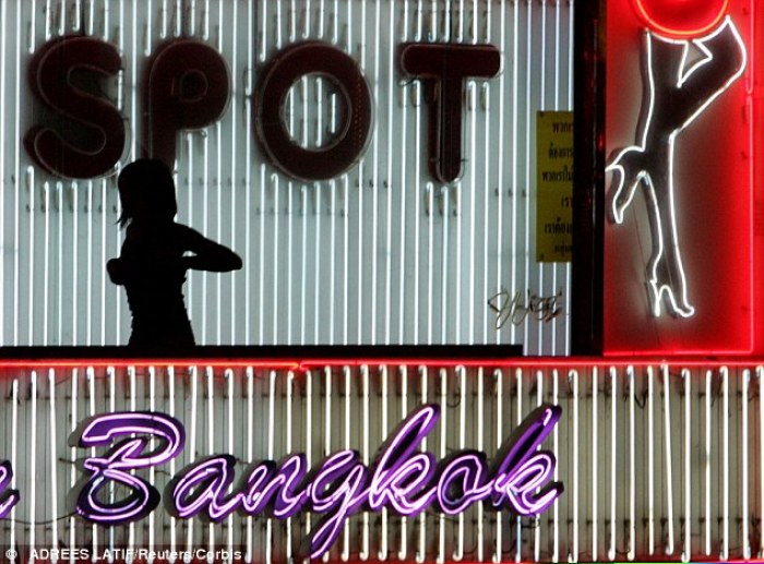 A sex worker adjusts her outfit while walking past a 'go go' bar in Bangkok's Nana Plaza on July 9, 2004.