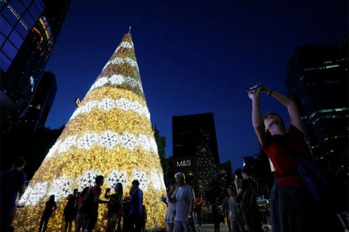 People take photos near a Christmas tree outside a mall at the shopping district of Orchard Road in Singapore December 21, 2017.