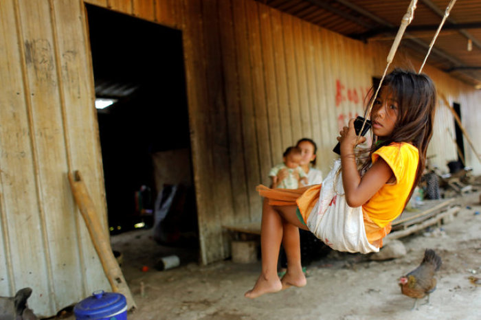 The daughter of a banana plantation worker swings outside her home at a plantation operated by a Chinese company in the province of Bokeo in Laos on April 26, 2017.
