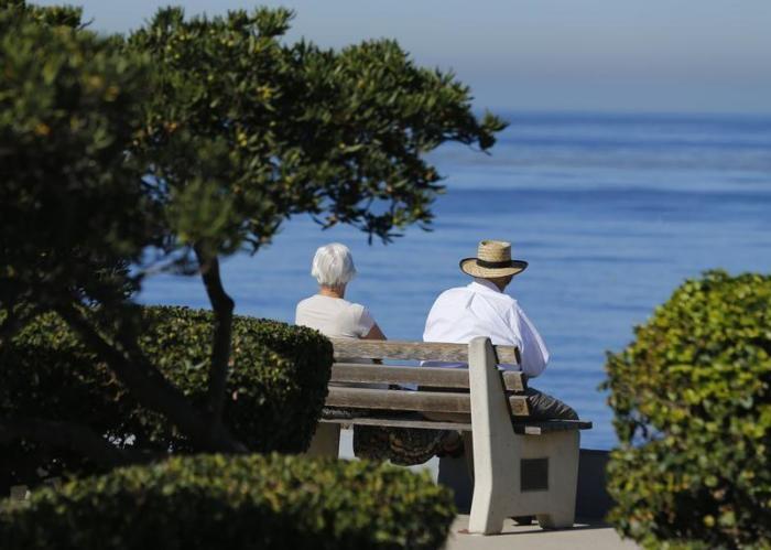 An elderly couple looks out at the ocean as they sit on a park bench in La Jolla, California November 13, 2013.