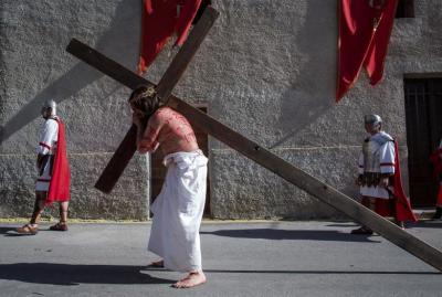 A local resident, playing the role of Jesus Christ, carries his cross during a Via Crucis representation on Good Friday in Cuevas del Campo, Spain.