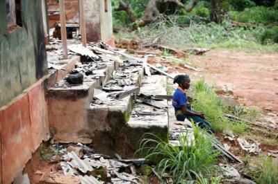 A woman attends a community dialogue meeting as she sits in front of a burnt building belonging to Christ Holy Church International in Uzo-Uwani village near Nimbo town in Nigeria's southeastern state of Enugu August 4, 2016.