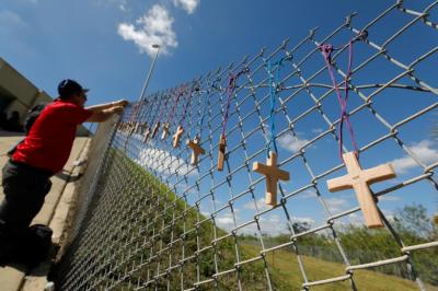 Bob Ossler, chaplain with the Cape Coral volunteer fire department, places seventeen crosses for the victims of yesterday's shooting at Marjory Stoneman Douglas High School on a fence a short distance from the school in Parkland, Florida, U.S., February 15, 2018.