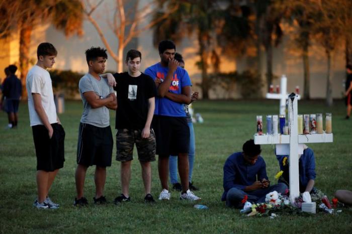 People mourn next to crosses placed in a park to commemorate the victims of the shooting at Marjory Stoneman Douglas High School, in Parkland, Florida, February 16, 2018.