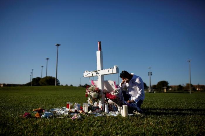 Joe Zevuloni mourns in front of a cross placed in a park to commemorate the victims of the shooting at Marjory Stoneman Douglas High School, in Parkland, Florida, February 16, 2018.