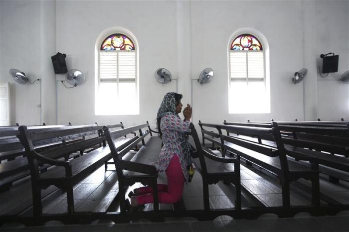 Woman prays at church in Malaysia.