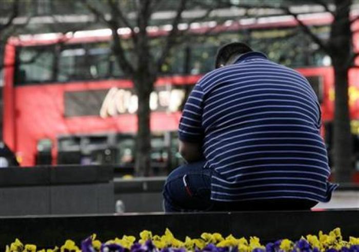 An obese man sits on a wall in the Canary Wharf financial district of London, April 1, 2009.