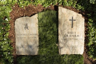 A slab of North Carolina stone marks the grave of Billy Graham, buried next to his wife, Ruth, at the Prayer Garden located next to the Billy Graham Library in Charlotte. The marker inscription bears the text, 'Preacher of the Gospel of the Lord Jesus Christ' with the Scripture reference, John 14:6.