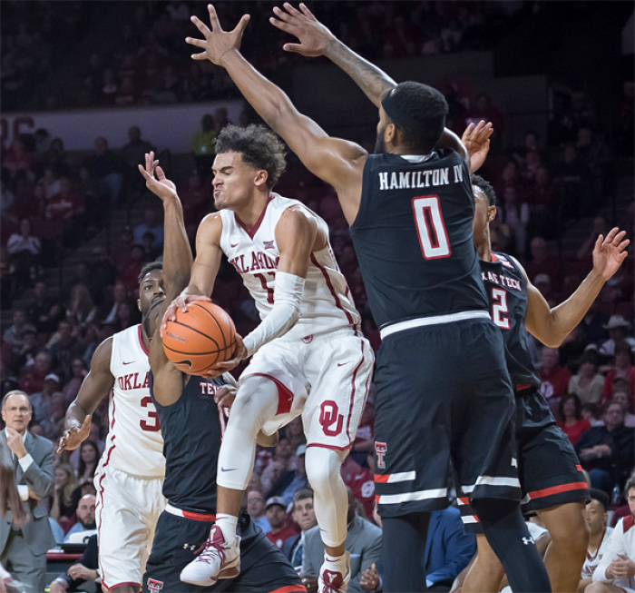 Oklahoma Sooners guard Trae Young before passing the ball defended by Texas Tech Red Raiders forward Tommy Hamilton IV.