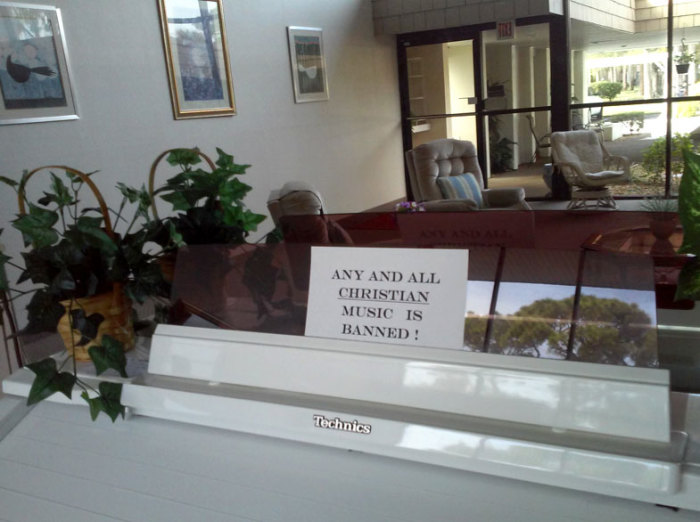 A sign that states that Christian music is banned sits on top of an organ located in a common room at the Cambridge House Condominiums in Port Charlotte, Florida.