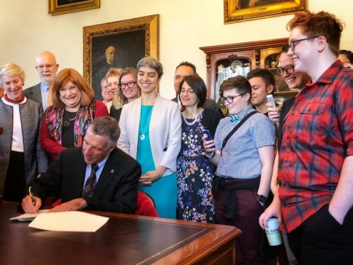 Republican Gov. Phil Scott of Vermont signs Vermont's gender-neutral bathroom bill into law on Friday May 11, 2018. He is surrounded by advocates and members of the states LGBTQ community.