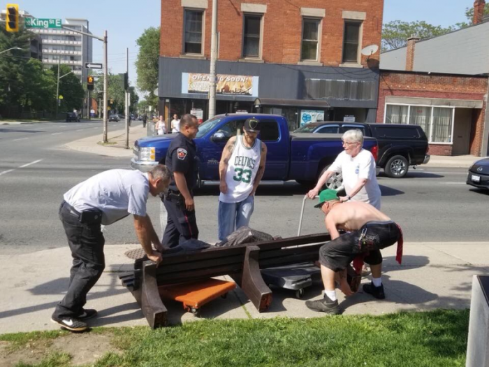 Passersby help pick up a 'Jesus the Homeless' statue outside of St. Patrick's Roman Catholic Church in Hamilton, Ontario, Canada after a junk-removal truck crashed into it on May 28, 2018.