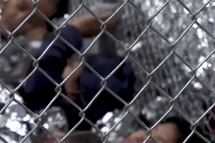 Screenshot of the video released by border patrol shows children waiting in a series of cages created by metal fencing.