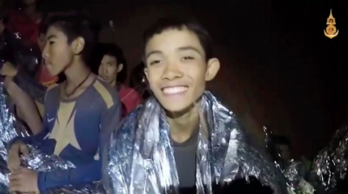 Thai boy smiles as Thai Navy SEAL medic helps injured children inside a cave in Mae Sai, northern Thailand,July 3, 2018,.