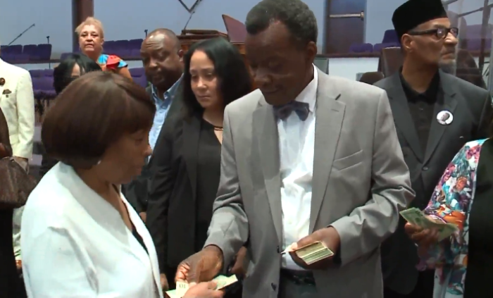 Chicago mayoral candidate Willie Wilson hands out cash to churchgoers at the New Covenant Missionary Baptist Church on Sunday July 22, 2018.