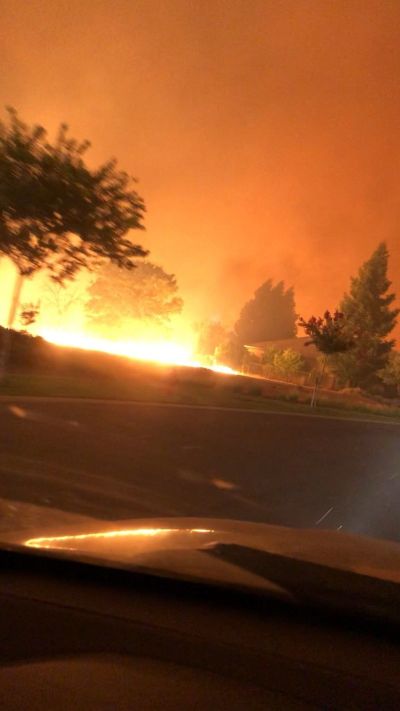 A neighborhood outside of Redding, California catches fire Thursday as residents escape by car.