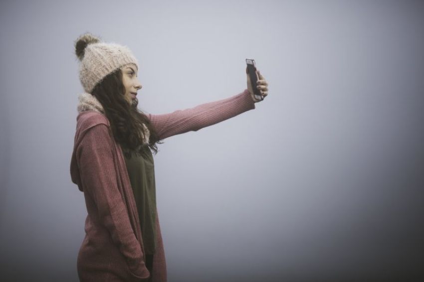 A woman takes a "selfie" picture with her cell phone.