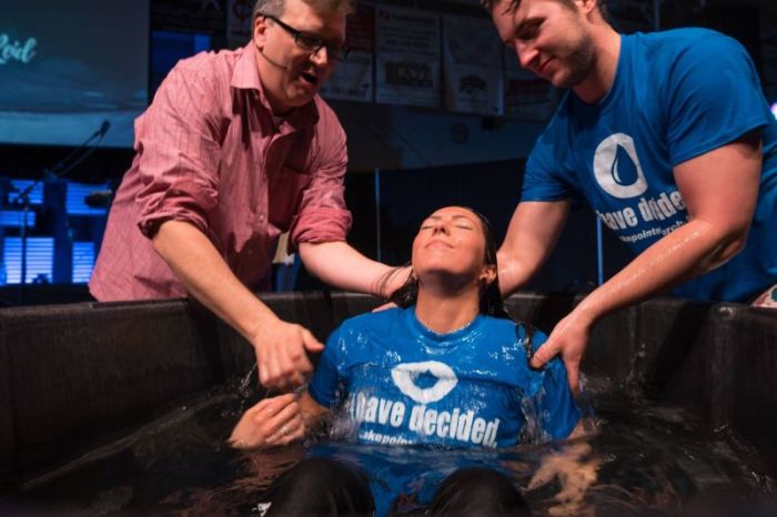 Pastor Scott Blanchard baptizes a female worshiper at Lakepointe Baptist Church, which holds its services at Lutheran North High School in Macomb, Michigan.