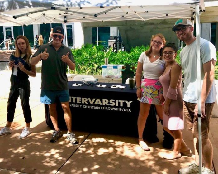 Campus staff Minister Zachary Alexander (right) at the University of South Florida in St. Petersburg gathers with students in front of an InterVarsity Christian Fellowship welcome table in August 2018.