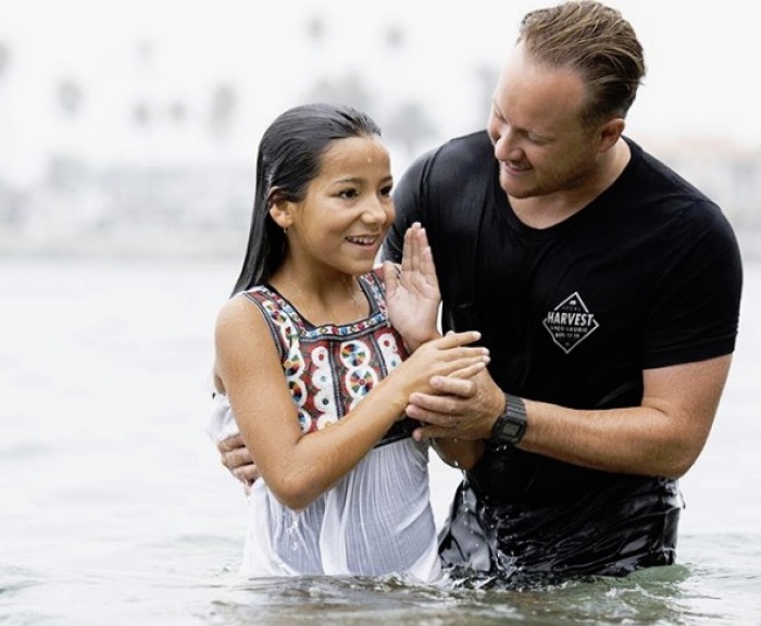Jonathan Laurie baptizes a girl at Pirates Cove Beach in Newport Beach, California on Sept. 8, 2018.