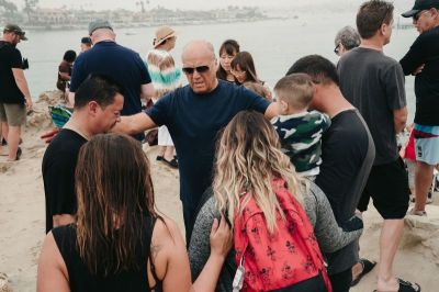 Evangelist Greg Laurie prays with people gathered at Pirates Cove Beach in Newport Beach, California on Sept. 8, 2018.