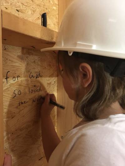 A girl writes scripture on the framing of the Piedmont Women's Center.