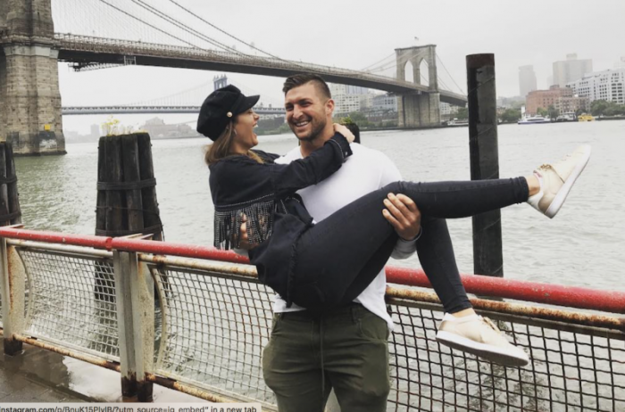 Tim Tebow hold up girlfriend Demi-Leigh Nel-Peters in fron tof Breooklyn Bridge, September 14, 2018.
